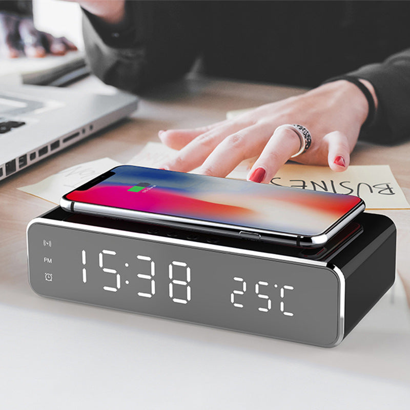 Modern LED alarm clock with wireless charger on a desk with a smartphone charging on top