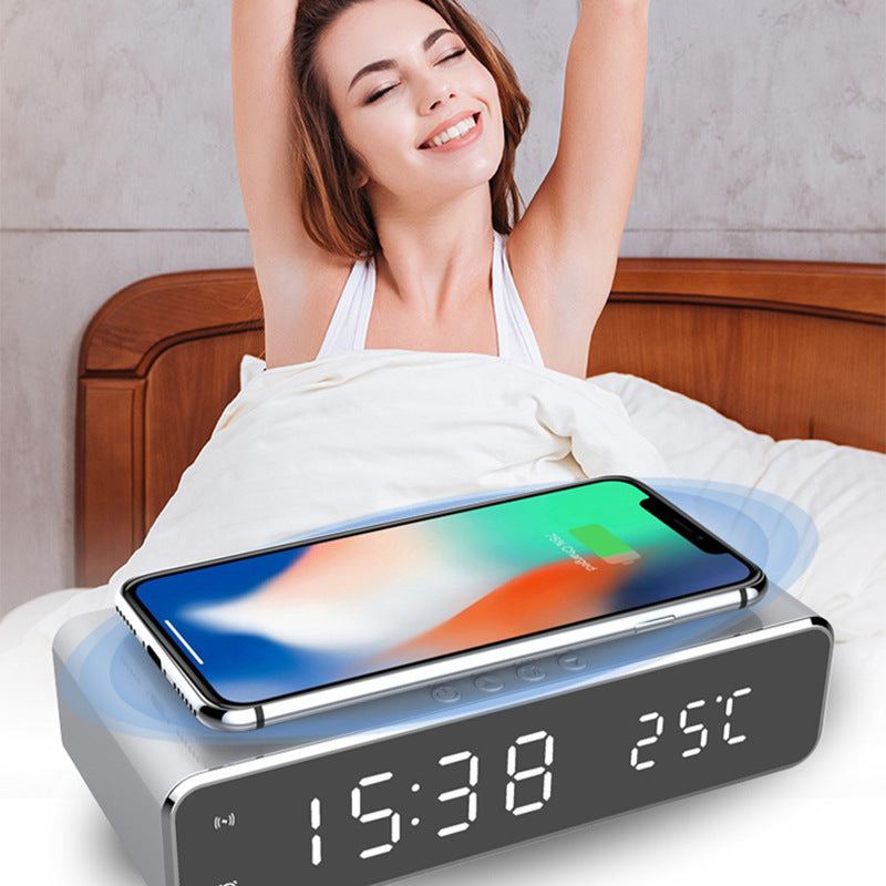 LED alarm clock with wireless charger displaying time and temperature beside a person waking up in bed
