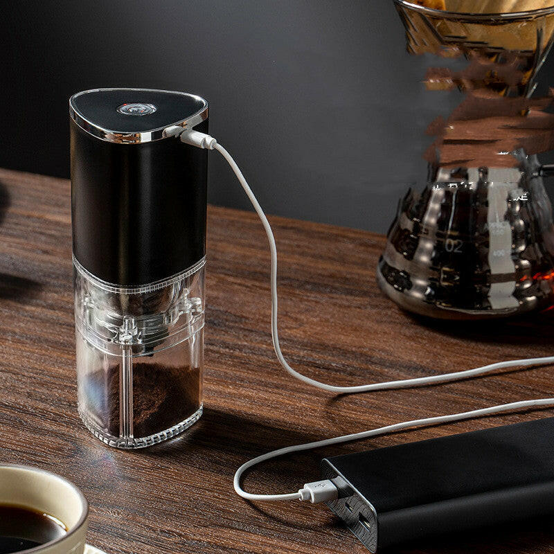 Mystore portable electric coffee grinder on a wooden table with fresh coffee and a power bank