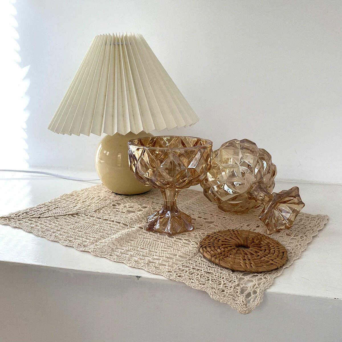 Vintage amber drinking glass with decorative elements and a lamp on a lace table runner