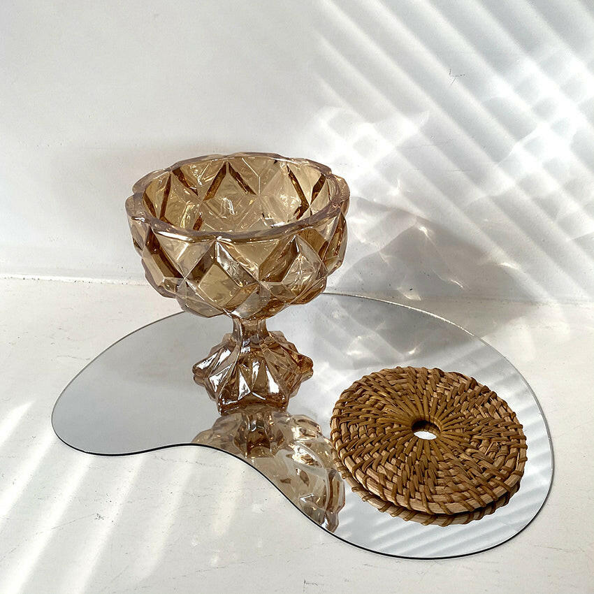 Vintage amber drinking glass with diamond cut design displayed on a reflective surface