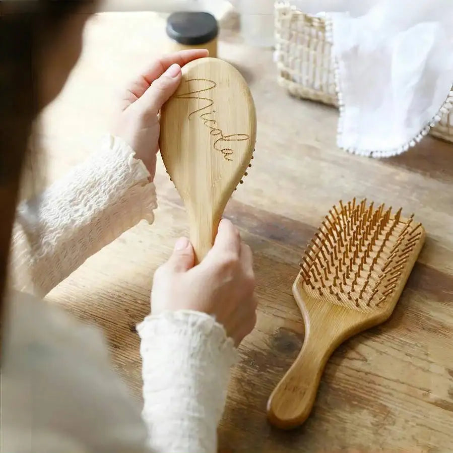 Custom engraved wooden hair brush with personalized name on a natural wooden surface