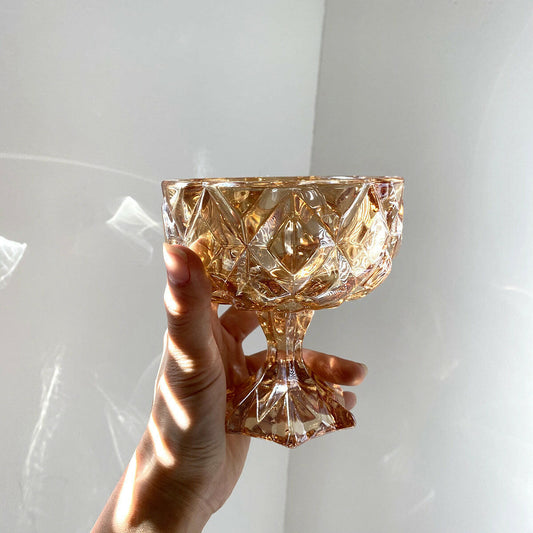 Handheld vintage amber drinking glass with a diamond pattern and elegant pedestal base
